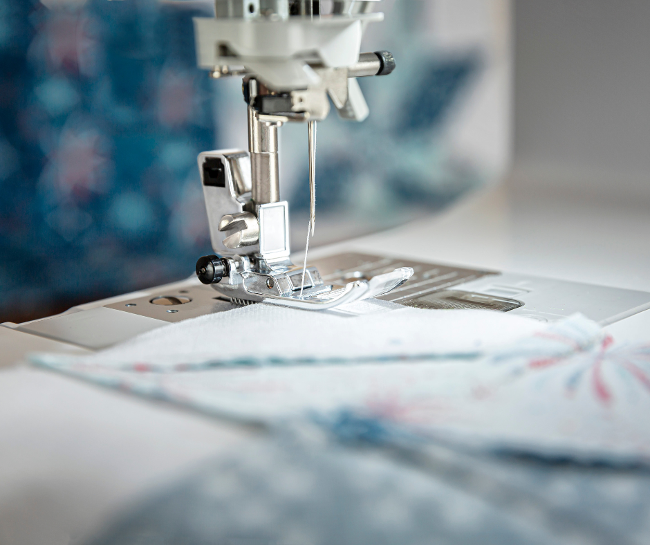 Sewing machine and hand quilting needles with thread and a thimble on a cutting mat