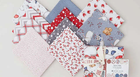 Fat quarter bundle of cotton quilt fabric featuring winter prints in a red, gray, and white palette.