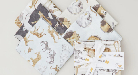 Fat quarters of animal prints with a Noah's ark theme in pale blue, taupe, charcoal, and cream.